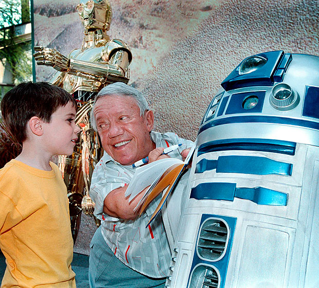 ORG XMIT: 324601_1.tif O ator Kenny Baker, que interpretou o rob R2-D2 no filme "Guerra nas Estrelas" assina autgrafo em Lake Buena Vista, EUA. Actor Kenny Baker, (C), who portrayed the droid R2-D2 (R) in all four "Star Wars" films, signs an autograph for Evan Dodson, 4, (L) of Gaithersburg, Maryland, 04 May, 2001 on opening day of "Star Wars Weekends at the Disney-MGM Studios" in Lake Buena Vista, Fla. Baker, who recently finished filming scenes for the next "Star Wars" film, is appearing through 06 May at the theme park. AFP PHOTO 