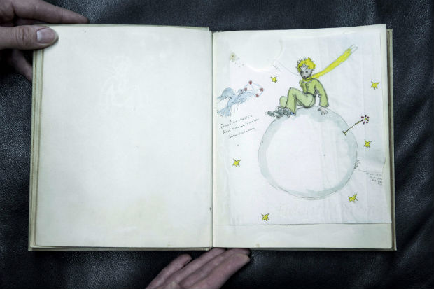 A drawing from an original color signed copy of "O Pequeno Prncipe" by late French author and aviator Antoine de Saint-Exupery, is pictured at the Cazo auction house on December 2, 2016 in Paris, on the eve of their sale. On December 3, Maison Cazo will be selling an original and signed copy of the Petit Prince which will be accompanied by two drawings by author Antoine de Saint-Exupery. The copy for sale at Cazo is an original color edition of the French version of the Little Prince published in New York in 1943 by Reynal & Hitchcock. This unpublished copy dedicated and accompanied by two original drawings is estimated by Cazo to sell between 80,000 and 100,000 euros. / AFP PHOTO / PHILIPPE LOPEZ / RESTRICTED TO EDITORIAL USE - MANDATORY MENTION OF THE ARTIST UPON PUBLICATION - TO ILLUSTRATE THE EVENT AS SPECIFIED IN THE CAPTION