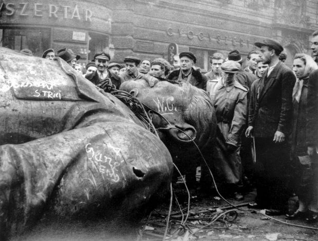  FILE - In this Oct. 24, 1956 file photo, people gather around a fallen statue of Soviet leader Josef Stalin in front of the National Theater in Budapest, Hungary. The uprising in Hungary began on Oct. 23, 1956 with demonstrations against the Stalinist regime in Budapest and was crushed eleven days later by Soviet tanks amid bitter fighting. For Hungary, a pro-Russian leader in the White House offers hope the Western world might end the sanctions imposed over Russia's annexation of Crimea and its role in eastern Ukraine. Many Poles, instead, fear a U.S-Russian rapprochement under Trump could threaten their own security interests. To most Poles, NATO represents the best guarantee for an enduring independent state in a difficult geographical neighborhood. (AP Photo/Arpad Hazafi, file) ORG XMIT: LON111
