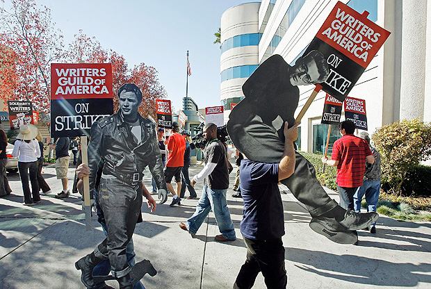 FILE - In this Nov. 26, 2007 file photo, striking writers carry live sized photos of legendary actors, Marlon Brando, left, and James Dean to express their support to members of the Writers Guild of America (WGA), outside the Raleigh Studios in Los Angeles. On Monday, April 10, 2017, the Writers Guild of America will pick up negotiations again with the Alliance of Motion Pictures and Television Producers, which represents broadcast networks and movie studios, over a new contract. The WGA is moving to authorize a strike, but Hollywood is hoping to avoid a work stoppage like the 100-day strike of 2007. (AP Photo/Damian Dovarganes, File) ORG XMIT: NY107