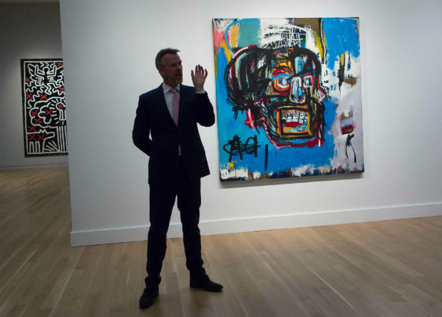 (FILES) This file photo taken on May 5, 2017 shows a Sotheby's official speaking about "Untitled," a 1982 painting by Jean-Michel Basquiat during a media preview at Sotheby's in New York. The work sold for $110.5 million on May 18, 2017, in New York, setting a new auction record for the US artist in Sotheby's flagship post-war and contemporary art sale, the auction house said. / AFP PHOTO / Don Emmert / RESTRICTED TO EDITORIAL USE - MANDATORY MENTION OF THE ARTIST UPON PUBLICATION - TO ILLUSTRATE THE EVENT AS SPECIFIED IN THE CAPTION