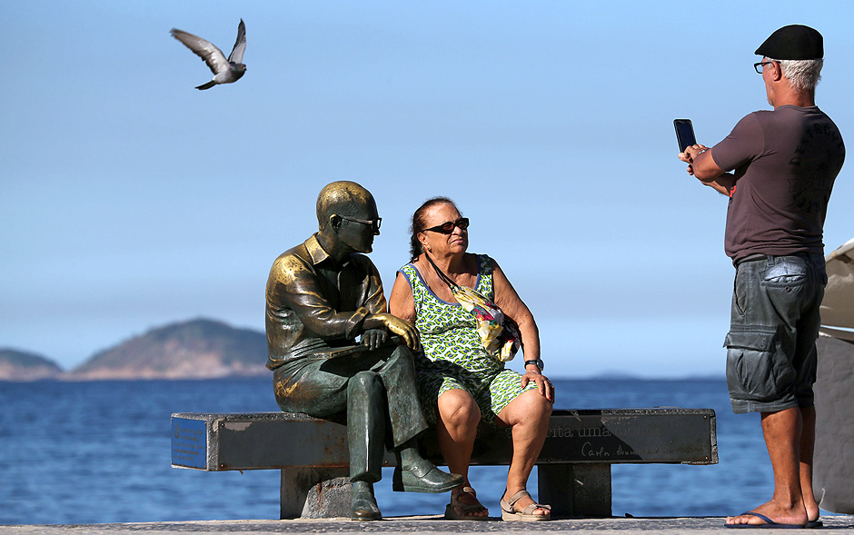 Mulher senta ao lado da esttua de Carlos Drummond de Andrade em Copacabana, no Rio