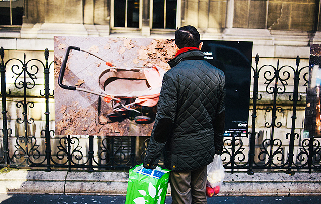 Um homem observa uma das fotografias expostas diante da prefeitura de Paris