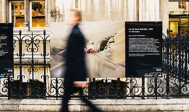 Um homem passa em frente a uma das fotografias expostas diante da prefeitura de Paris