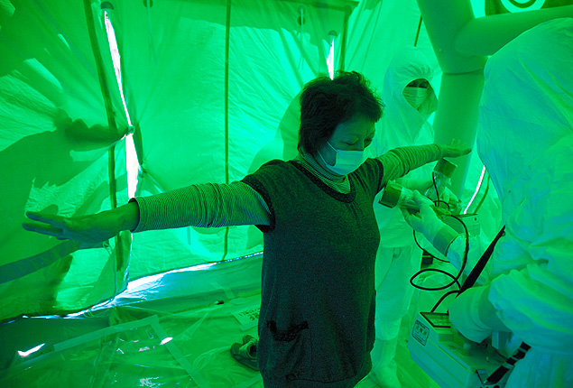 Equipe mdica escaneia mulher exposta a radiao perto da planta nuclear de Fukushima, em 2011