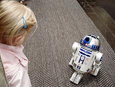 Robô R2-D2 de "Guerra nas Estrelas" observa garota na feira de informática Cebit
