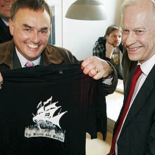 Advogados de defesa do Pirate Bay seguram camiseta com logo do site durante o julgamento