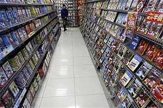 Mulher caminha em loja de DVDs em Taiwan; General Electric anuncia a produção de disco holográfico com capacidade para cem DVDs