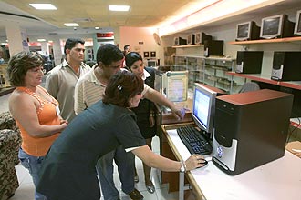 Empregados de uma loja de eletrônicos examinam computadores em Havana; jornal protesta contra bloqueio do MSN no país