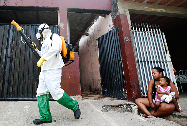 A health official walks past residents as he carries out fumigation to help control the spread of dengue fever in Sao Paulo