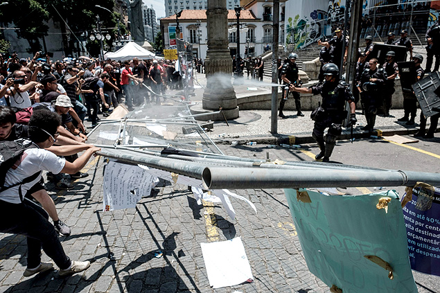 Rio de Janeiro state's public servants break a metal fence during a protest against austerity measures in front of the Rio de Janeiro state Assembly (ALERJ), where lawmakers began discussing the measures promoted by the governor Luiz Fernando Pezao pushing budget cuts in response to nearly empty public coffers, in Rio de Janeiro, Brazil, on November 16, 2016. / AFP PHOTO / YASUYOSHI CHIBA