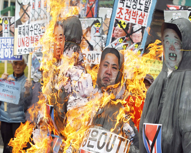 Manifestantes ateiam fogo em bonecos dos ditadores norte-coreanos Kim Il-sung, Kim Jong-un e Kim Jong-il, em Seul