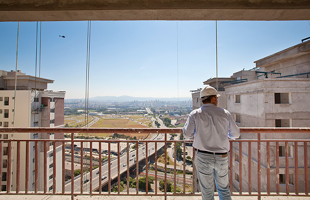 Engenheiro observa a obra de torres residenciais e comerciais na sacada de apartamento