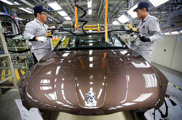 Employees work at a production line of a Dongfeng Peugeot Citroen Automobile factory in Wuhan, Hubei province, in this February 13, 2014 file picture. The chairman of China's Dongfeng Motor Group said on March 28, 2014 that cooperation with French carmaker PSA Peugeot Citroen is not limited to the Asia-Pacific, and that Brazil and Russia are possible future markets. The Asia-Pacific region is just a "starting point" for the two firms' collaboration, Donfeng chairman Xu Ping told a media briefing in Beijing. The two companies officially signed an alliance earlier this week that will give a much-needed cash injection to the troubled French automaker. The two firms, which have a well-established joint venture in China, announced they would deepen their business in the country and planned to triple total sales to 1.5 million vehicles by 2020. They also aim to jointly build a presence in Southeast Asia. REUTERS/Stringer/Files (CHINA - Tags: TRANSPORT BUSINESS) CHINA OUT. NO COMMERCIAL OR EDITORIAL SALES IN CHINA ORG XMIT: FIL58