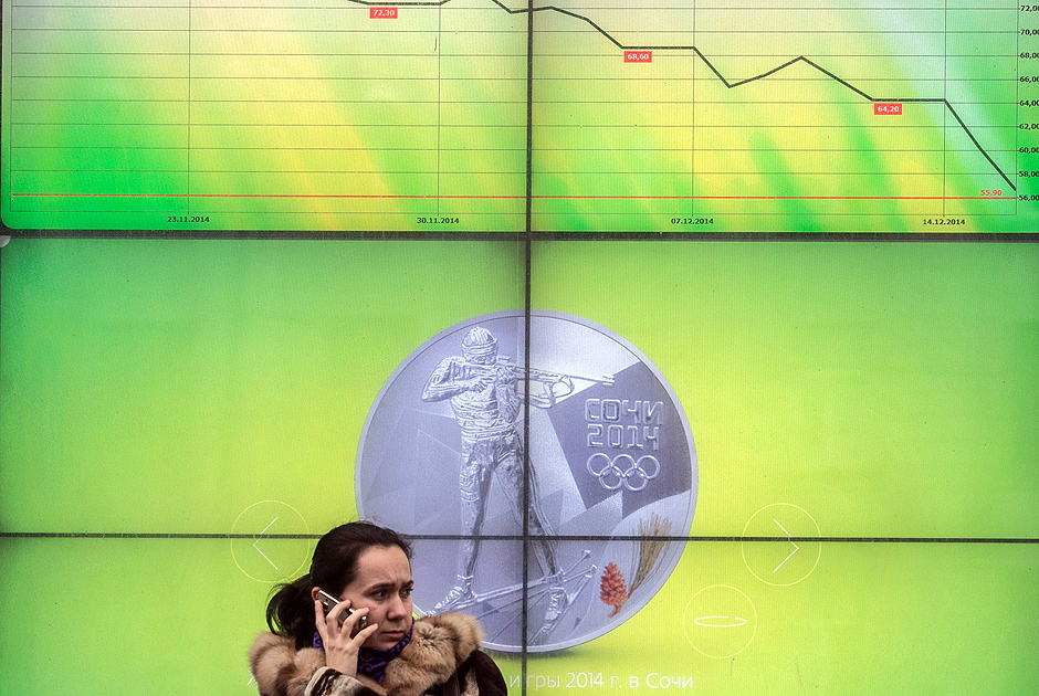 Russa fala ao telefone enquanto painel de banco mostra cotao do rublo em dezembro 