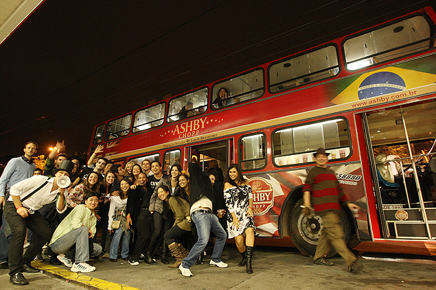 Participantes de excurso, muitos estrangeiros, posam para foto em frente de nibus de dois andares, em tour pelos bares e casas noturnas da cidade de So Paulo