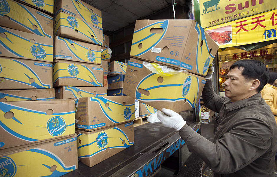 Entregador descarrega caixas de bananas 