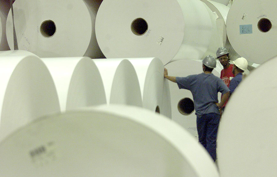 Funcionrios da Suzano Papel e Celulose em meio a bobinas de papel carto da linha de acabamento