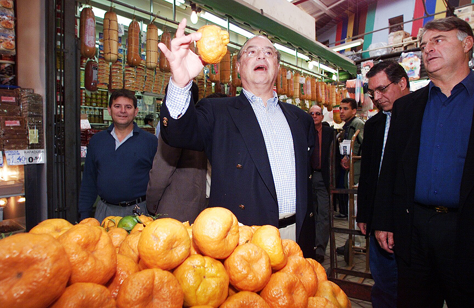 O então candidato Paulo Maluf segura uma mexerica durante visita ao no Mercado Municipal da Lapa em 2000
