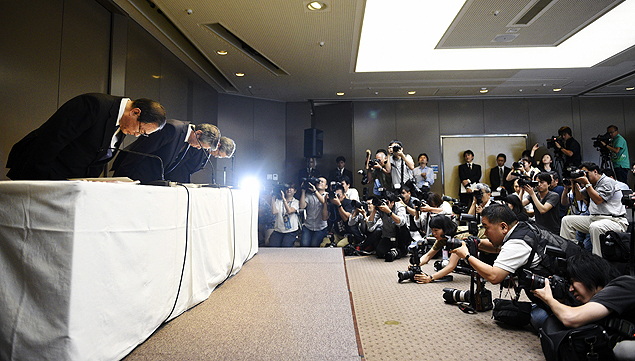 O presidente honorrio da Toshiba, Masashi Muromachi (esq), o presidente de Toshiba, Hisao Tanaka (centro) e o vice-presidente executivo Keizo Maeda (ao fundo), fazem uma reverncia durante a renncia de Tanaka