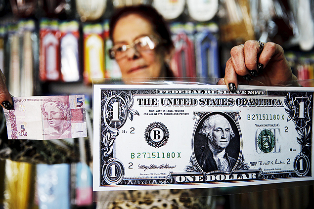 Una mujer sostiene un billete gigante de un dólar y otro de cinco reales dentro de una tienda en Itu, en las afueras de São Paulo