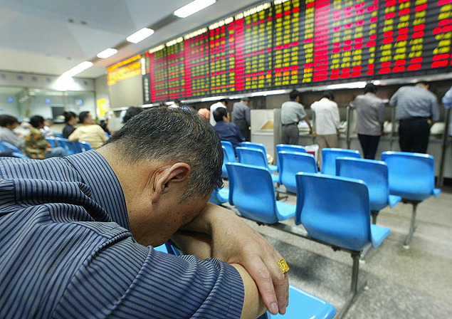 Investidor tira cochilo diante de painel eletrnico da Bolsa de Valores de Xangai (China)