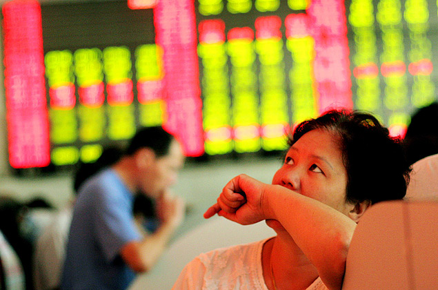 Investidora olha painel com cotao de aes na Bolsa de Valores de Xangai (China)
