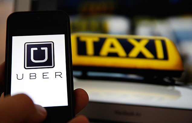 File illustration picture showing the logo of car-sharing service app Uber on a smartphone next to the picture of an official German taxi sign in Frankfurt, September 15, 2014. A Frankfurt court earlier this month instituted a temporary injunction against Uber from offering car-sharing services across Germany. San Francisco-based Uber, which allows users to summon taxi-like services on their smartphones, offers two main services, Uber, its classic low-cost, limousine pick-up service, and Uberpop, a newer ride-sharing service, which connects private drivers to passengers - an established practice in Germany that nonetheless operates in a legal grey area of rules governing commercial transportation. REUTERS/Kai Pfaffenbach/Files (GERMANY - Tags: BUSINESS EMPLOYMENT CRIME LAW TRANSPORT) ORG XMIT: KAI09