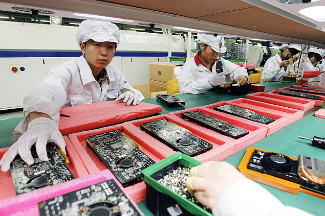 Funcionrios trabalham na linha de produo da Foxcoon, em Shenzhen, na China. A empresa  responsvel pela produo dos telefones smartphones da Apple, os iPhones. *** FILE - In this May 26, 2010 file photo, staff members work on the production line at the Foxconn complex in the southern Chinese city of Shenzhen. The company that makes Apple's iPhones suspended production at a factory in China on Monday, Sept. 24, 2012, after a brawl by as many as 2,000 employees at a dormitory injured 40 people. The fight, the cause of which was under investigation, erupted Sunday night at a privately managed dormitory near a Foxconn Technology Group factory in the northern city of Taiyuan, the company and Chinese police said. (AP Photo/Kin Cheung, File)