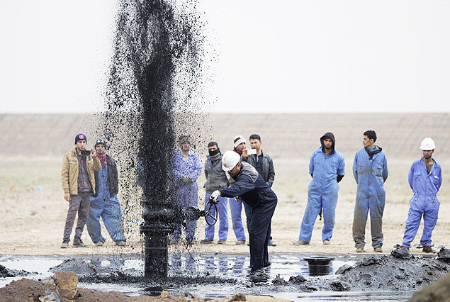 Trabalhadores iraquianos perto de um oleoduto, no campo petrolfero "Al Tuba", em Basra