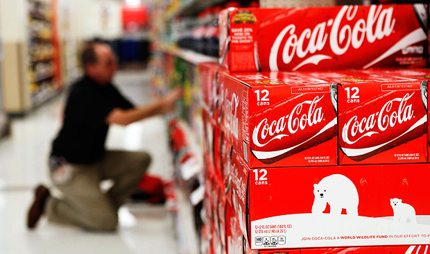An employee arranges bottles of Coca-Cola at a store in Alexandria, Virginia October 16, 2012. Coca-Cola Co reported a slightly higher-than-expected profit February 10, 2015 as sales in North America, its biggest market, rose for the first time in four quarters, offsetting the impact of a stronger dollar on its overseas business. REUTERS/Kevin Lamarque/Files (UNITED STATES - Tags: BUSINESS) ORG XMIT: TOR125