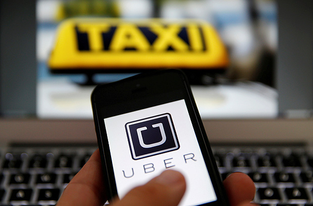 An illustration picture shows the logo of car-sharing service app Uber on a smartphone next to the picture of an official German taxi sign September 15, 2014. REUTERS/Kai Pfaffenbach/Illustration/File Photo ORG XMIT: INK103