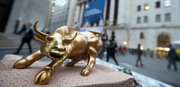 In this Tuesday, Oct. 25, 2016, photo, a miniature reproduction of Arturo Di Modica's "Charging Bull" sculpture sits on display at a street vendor's table outside the New York Stock Exchange, in lower Manhattan. Global stock markets were mixed on Wednesday, Nov. 16, 2016, as investors awaited more policy details from U.S. President-elect Donald Trump. Oil prices retreated, snapping an overnight rally. (AP Photo/Mary Altaffer) ORG XMIT: NY113