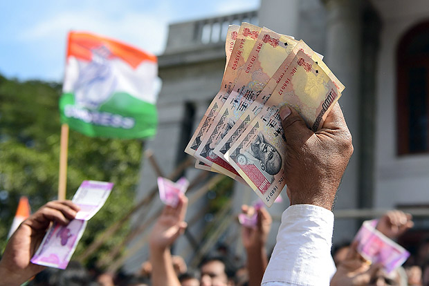 Indian supporters of the Congress Party hold Indian currency notes during a protest against the decision to demonitise 500 and 1000INR notes in Bangalore on November 28, 2016. Tens of thousands of people turned out November 28 for nationwide protests against India's controversial ban on high-value banknotes, which opposition party organisers say has caused a "financial emergency". / AFP PHOTO / Kiran MANJUNATH ORG XMIT: MK022