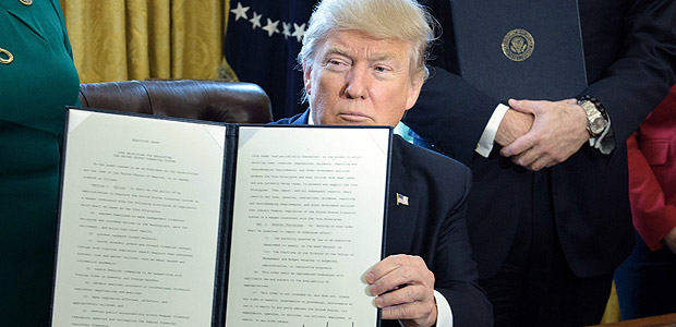 US President Donald Trump shows an executive order directing the Treasury Secretary to review the Dodd-Frank financial oversight law in the Oval Office of the White House on February 3, 2017 in Washington, DC. / AFP PHOTO / Brendan Smialowski