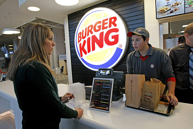 FILE - In a Saturday, Dec. 22, 2012 file photo, a customer purchases a meal at a Burger King restaurant in Marseille-Provence airport, in Marignane, France. Burger King is in talks to buy Tim Hortons in hopes of creating a new, publicly traded company with its headquarters in Canada. (AP Photo/Claude Paris, File) ORG XMIT: NY112
