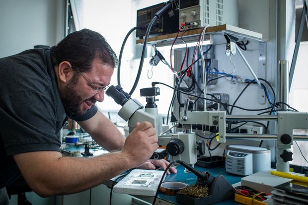 Bruno Jos, fundador da rede BR4 Iphone, opera microscpio usado no reparo de celulares, na matriz da rede, em Higienpolis