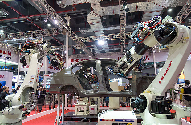 This picture taken on November 3, 2015 shows visitors watching robots welding a car at the 17th China International Industry Fair (CIIF) in Shanghai. The fair will be held from November 3 to 7 with 2,270 exhibitors from 28 countries and regions participating. CHINA OUT AFP PHOTO ORG XMIT: QT1078