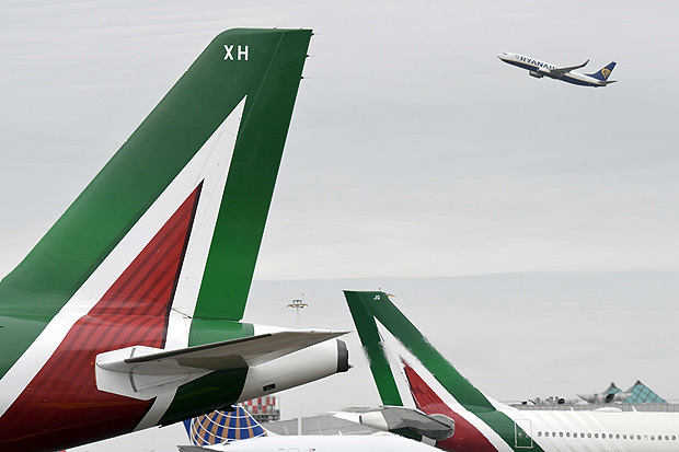 (FILES) This file photo taken on April 28, 2017 shows a plane of low-cost airline company Ryanair taking-off as planes of the Italian airline company Alitalia are parked at Rome's Fiumicino airport. Shareholders in Alitalia voted unanimously on May 2, 2017 to put the company into administration, moving the troubled airline a step closer to liquidation as efforts continue to find a buyer.The move follows last week's rejection by staff of job and salary cuts which management had proposed as a condition for injecting new funds under a two-billion-euro rescue plan for the loss-making company. / AFP PHOTO / Tiziana FABI