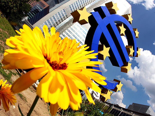 ORG XMIT: PFRA107 A sunflower stands in front of the Euro sculpture in Frankfurt, Germany, Thursday, July 5, 2012. The European Central Bank has cut its key interest rate by a quarter percentage point to a record low of 0.75 percent to boost a eurozone economy weighed down by the continent's crisis over too much government debt. The move followed a rate cut by China's central bank and new stimulus measures by the Bank of England as global financial authorities seek to shore up a slowing global economy. European leaders last week agreed on new steps to strengthen market confidence in their shared euro currency bloc. They agreed to set up a single banking supervisor to keep bank bailouts from bankrupting countries and made it easier for troubled countries to get bailout help. Those steps helped calm financial markets, which have expected the ECB to follow up with more help in the form of a rate cut. (AP Photo/Michael Probst)