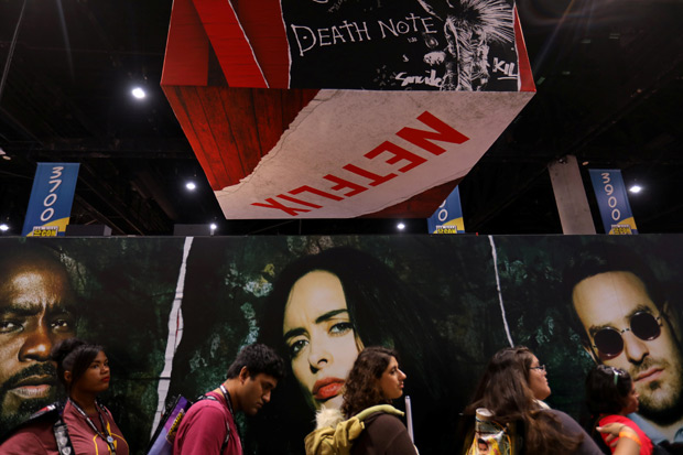 Visitantes de feira de quadrinhos em San Diego, nos EUA, passam por banner da Netflix