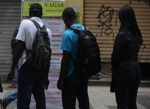 Pessoas olham cartazes com ofertas de vagas no centro de So Paulo