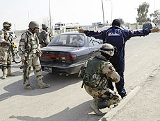 Soldado iraquiano revista motorista em posto de controle em Basra, no sul do pas