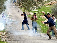 Grupo de palestinos lanam pedras durante protesto contra construo de barreira