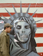 Policial iraniano em frente a mural, na embaixada dos EUA em Teer
