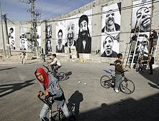 Meninos palestinos andam de bicicleta em frente a muro que divide Israel da Cisjordnia 
