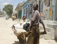 Homem foge dos confrontos em Mogadcio levando carrinho com menina e pertences