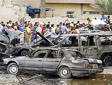 Iraquianos cercam carros destrudos em Bagd; trs ataques matam ao menos 115