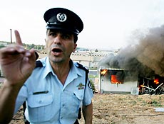 Policial israelense gesticula em frente a casa aps ataque de foguete palestino em Sderot