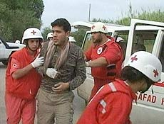 Membros da Cruz Vermelha libanesa socorrem palestino ferido em confronto